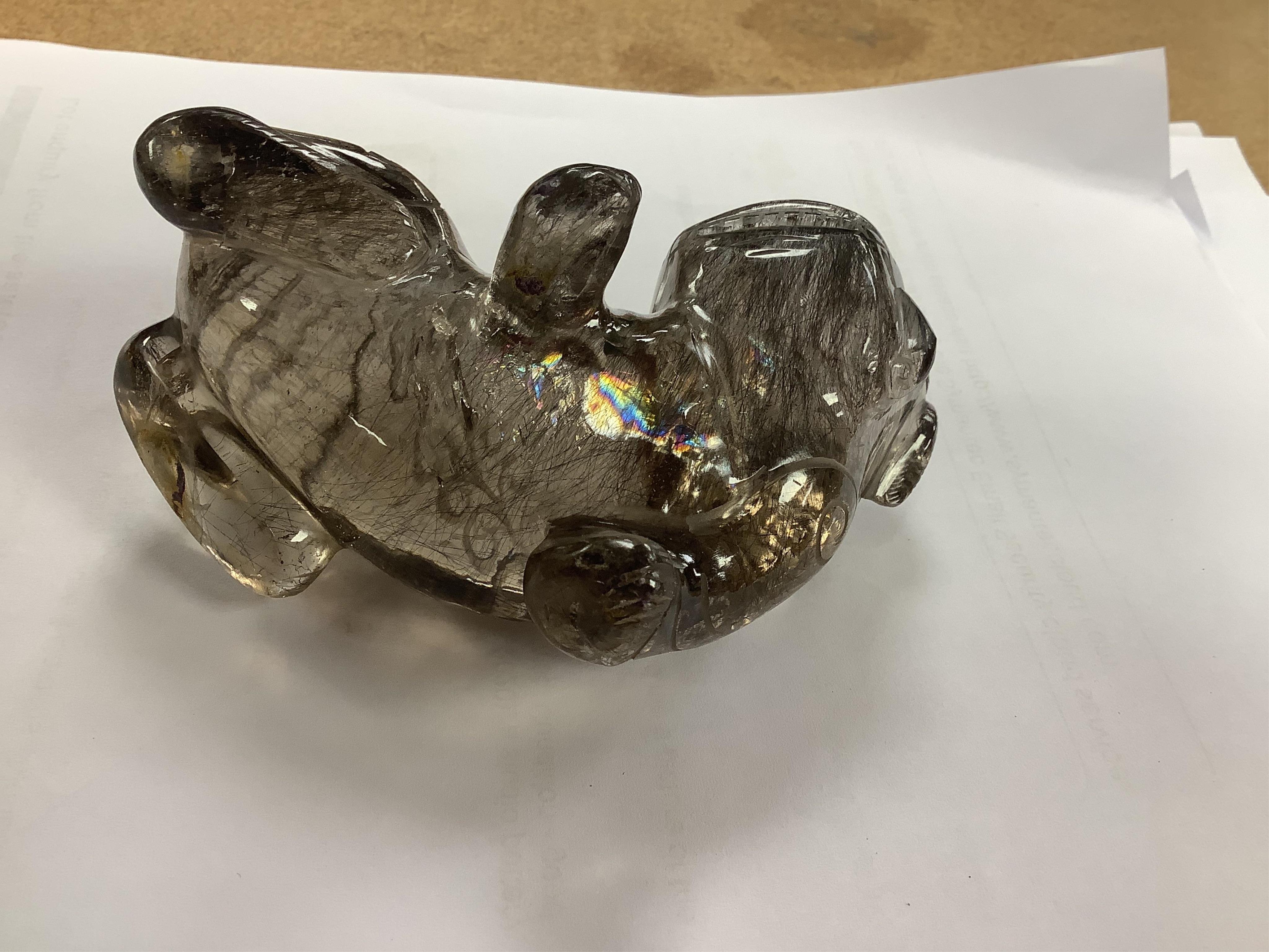 A Chinese carved smoky quartz lion dog on hardwood stand, 9.5cm wide. Condition - fair, impact damage to tail
